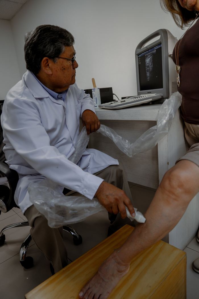 Doctor realizando un Eco Doppler en la pierna de una paciente